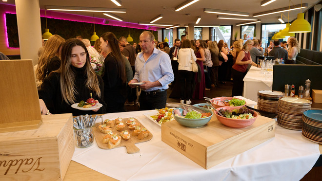 äste unterhalten sich beim Apéro nach der Diplomfeier an einem reichhaltigen Buffet.